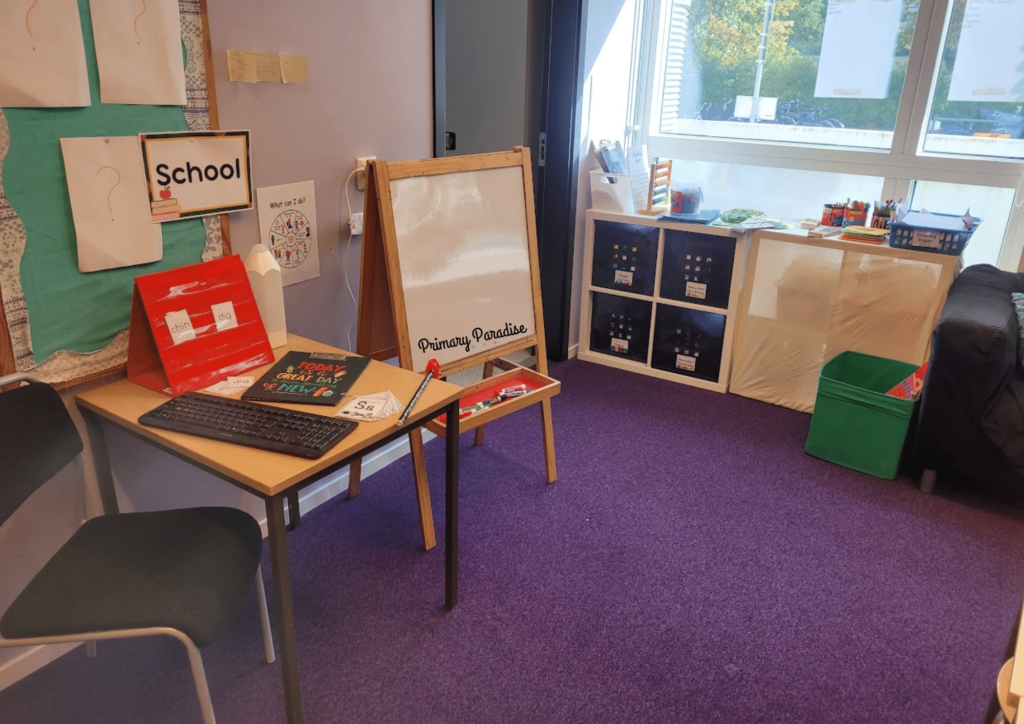 an image of a school center with an easel, big books, chalk, and other various school supplies