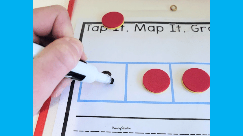 A hand with a marker writing a letter on a word mapping template