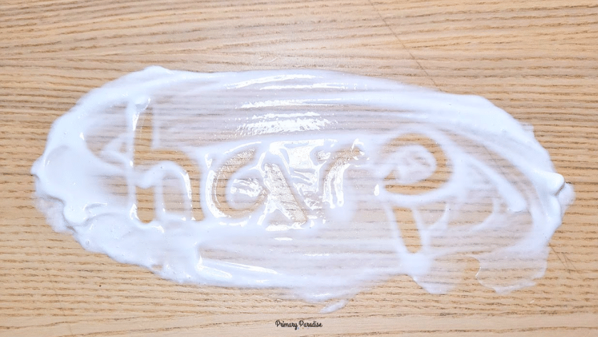 Shaving cream is spread on a wooden table. The word harp is written in the shaving cream.