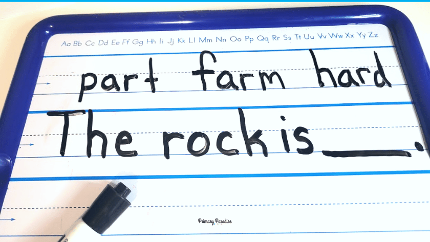 A dry erase board has the word part, farm, and hard on the top line. Underneath is the sentence "The rock is ___."
