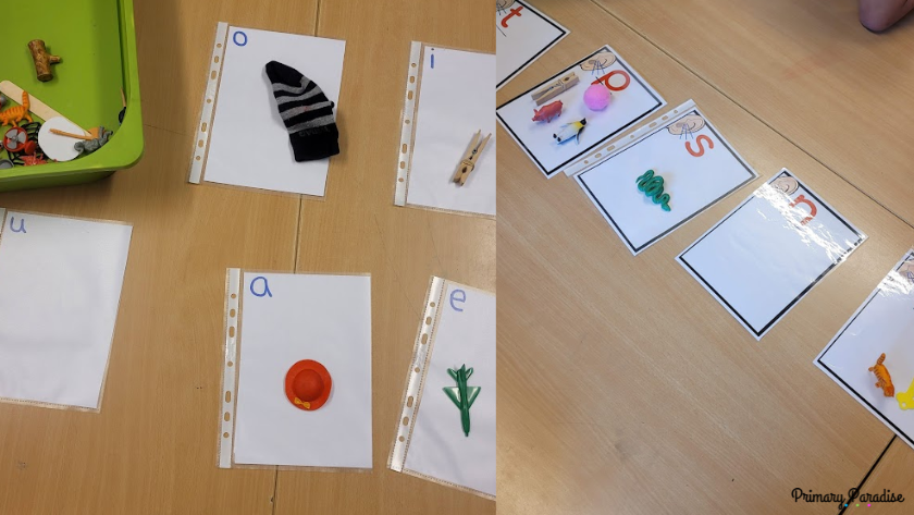 A letter sound sorting activity with mats with a letter and small objects that begin with the sound that letter represents. One side has vowels and the other side has consonants.