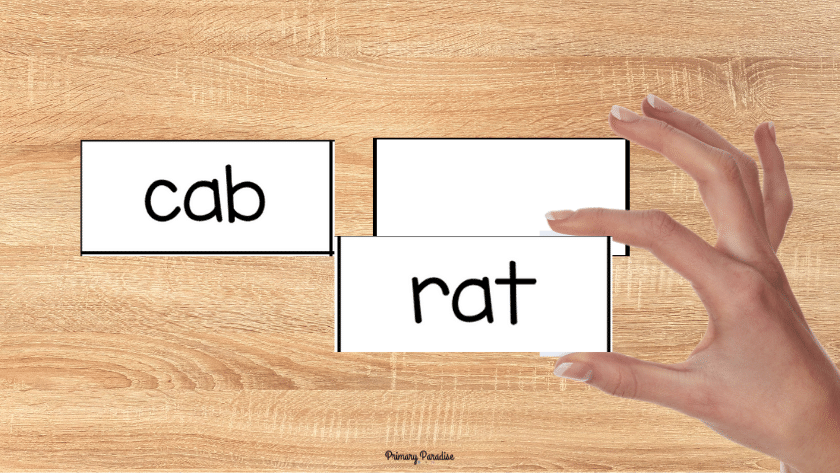 CVC word cards, one pile upsidedown and one side flipped over. A hand is holding