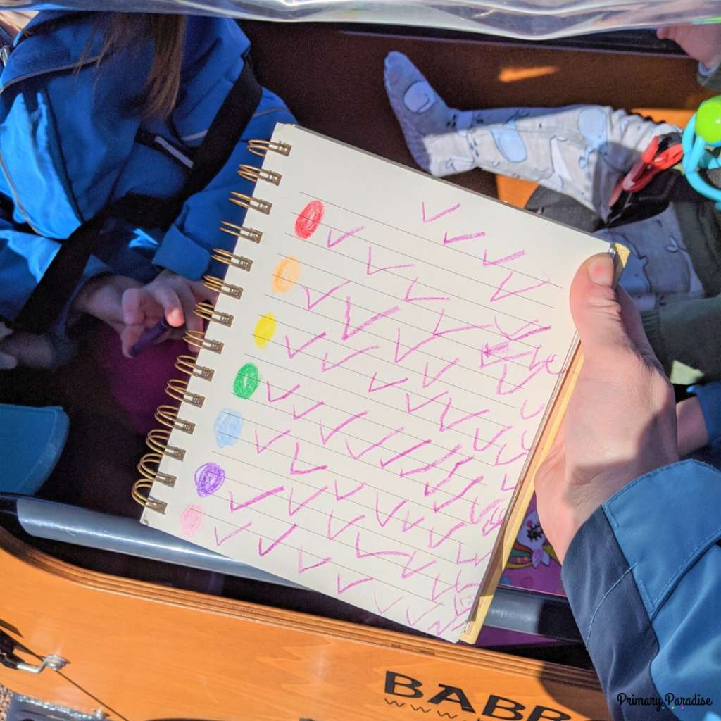 a hand holding a notebook: there are colored circles on the left with check marks next to them