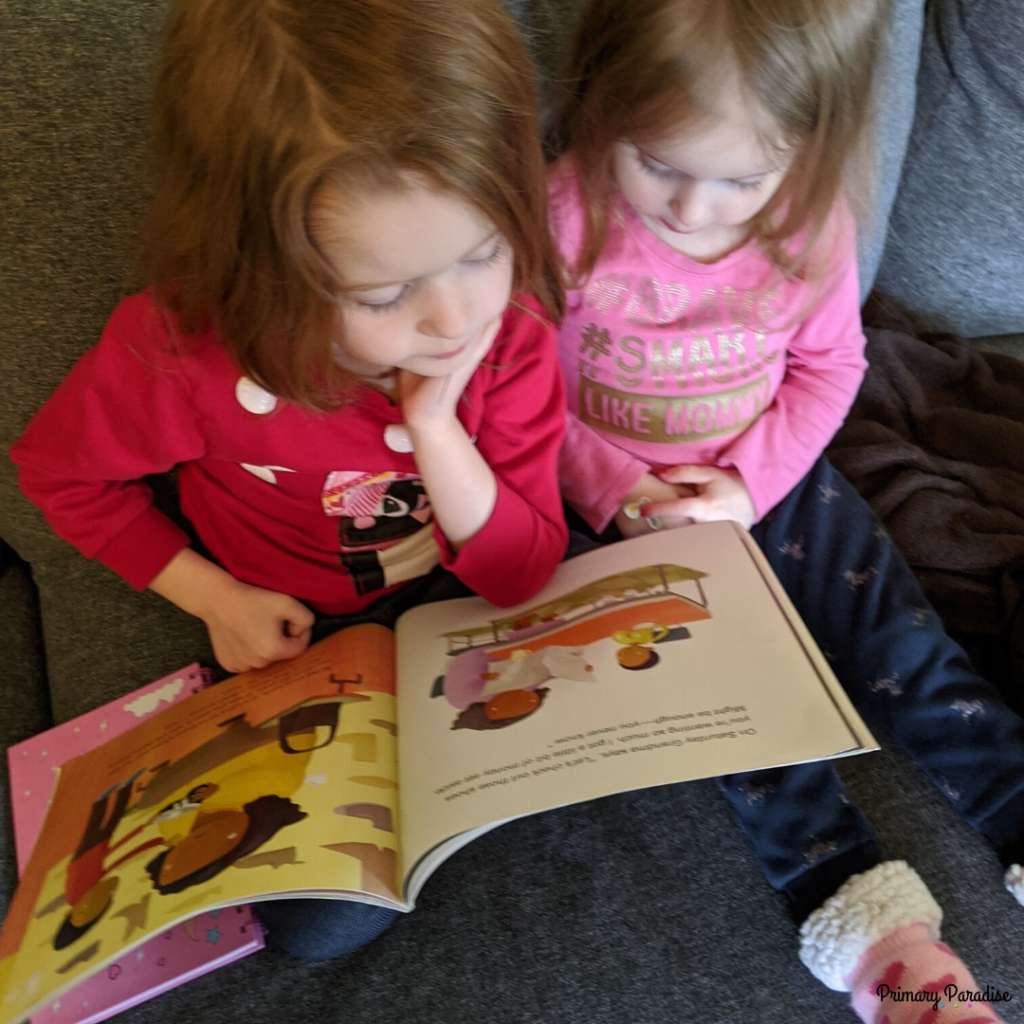 two little girls reading a book together